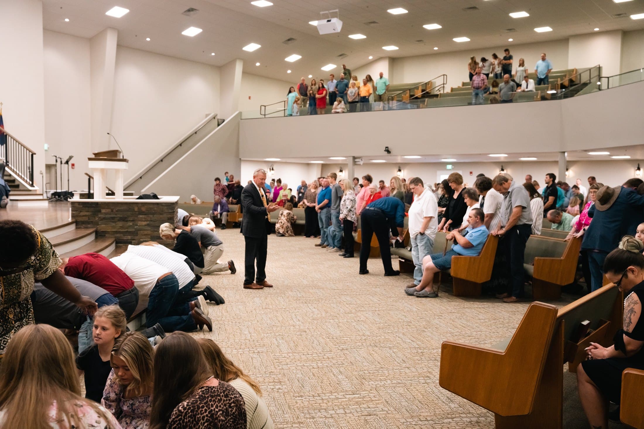The sanctuary during an invitation, with people kneeling at the front and the balcony filled behind them