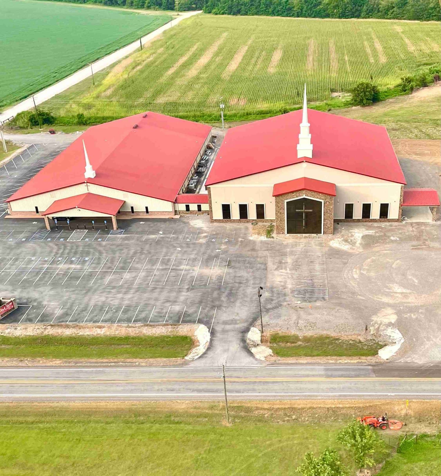 An aerial view of the Maple Springs church campus — two red-roofed buildings joined by a connector, with a large parking lot in front