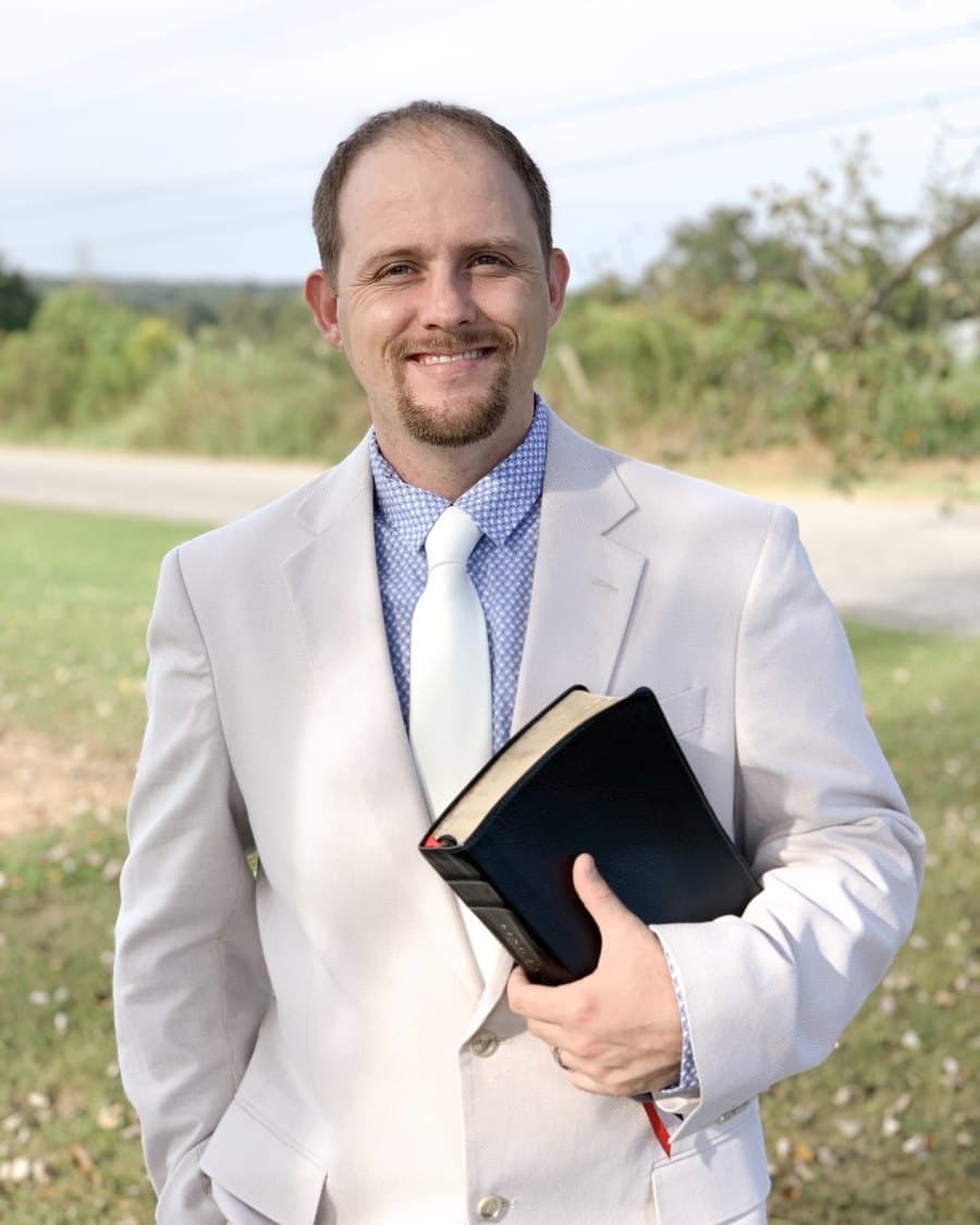 Bro. Shannon Fennell, assistant pastor, outdoors in a light jacket holding his Bible